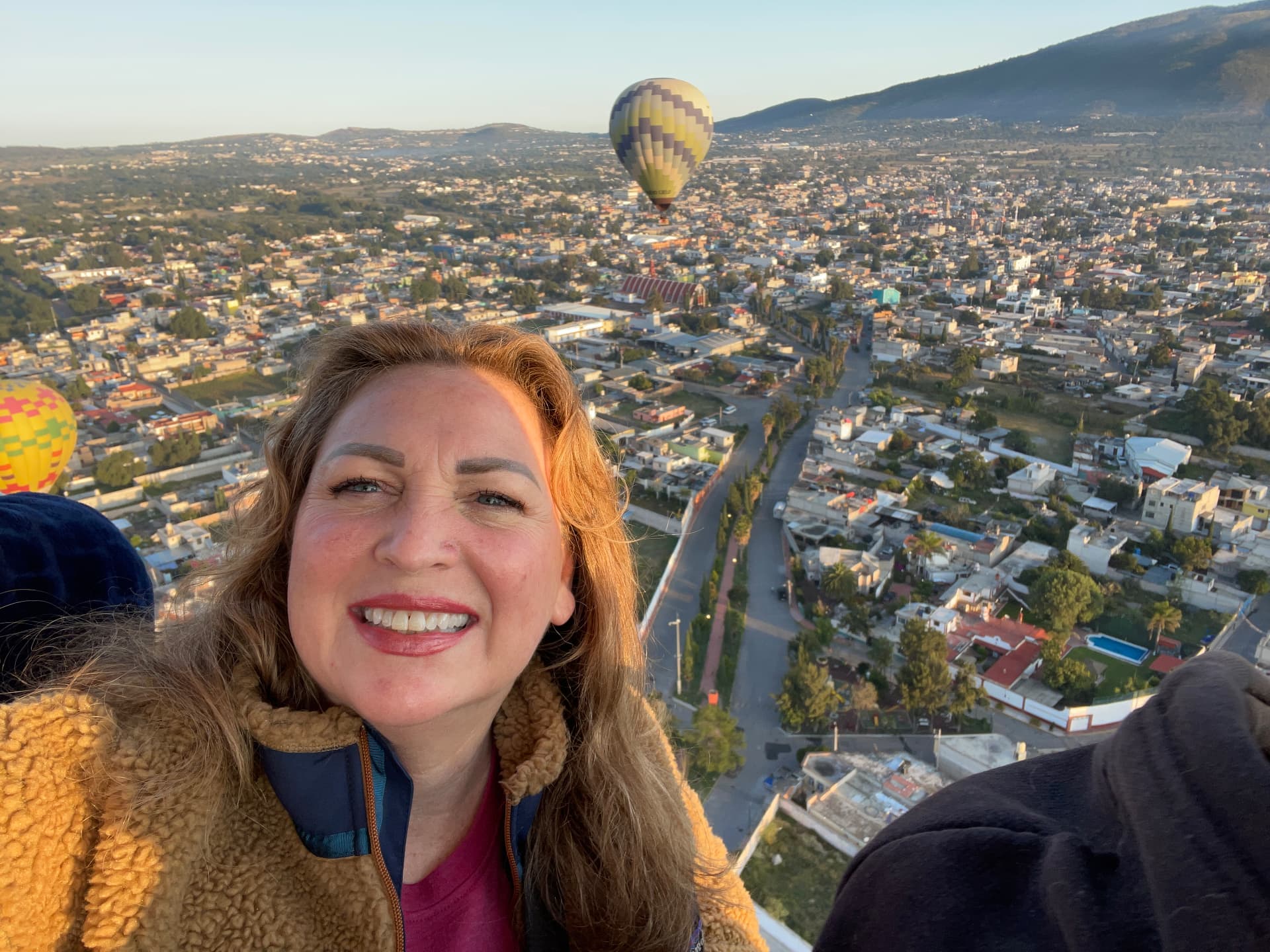 Phalynn smiling in a hot air balloon at sunrise